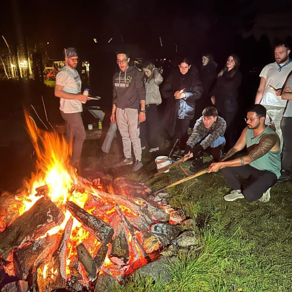 Grupa osób stojąca przy ognisku.